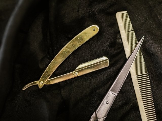 curso de barbeiro online- tesoura, navalha e pente em cima de um pano preto