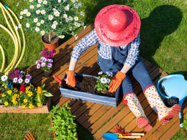 mulher com chapeu plantando flores sentada na grama. Melhores hobbies